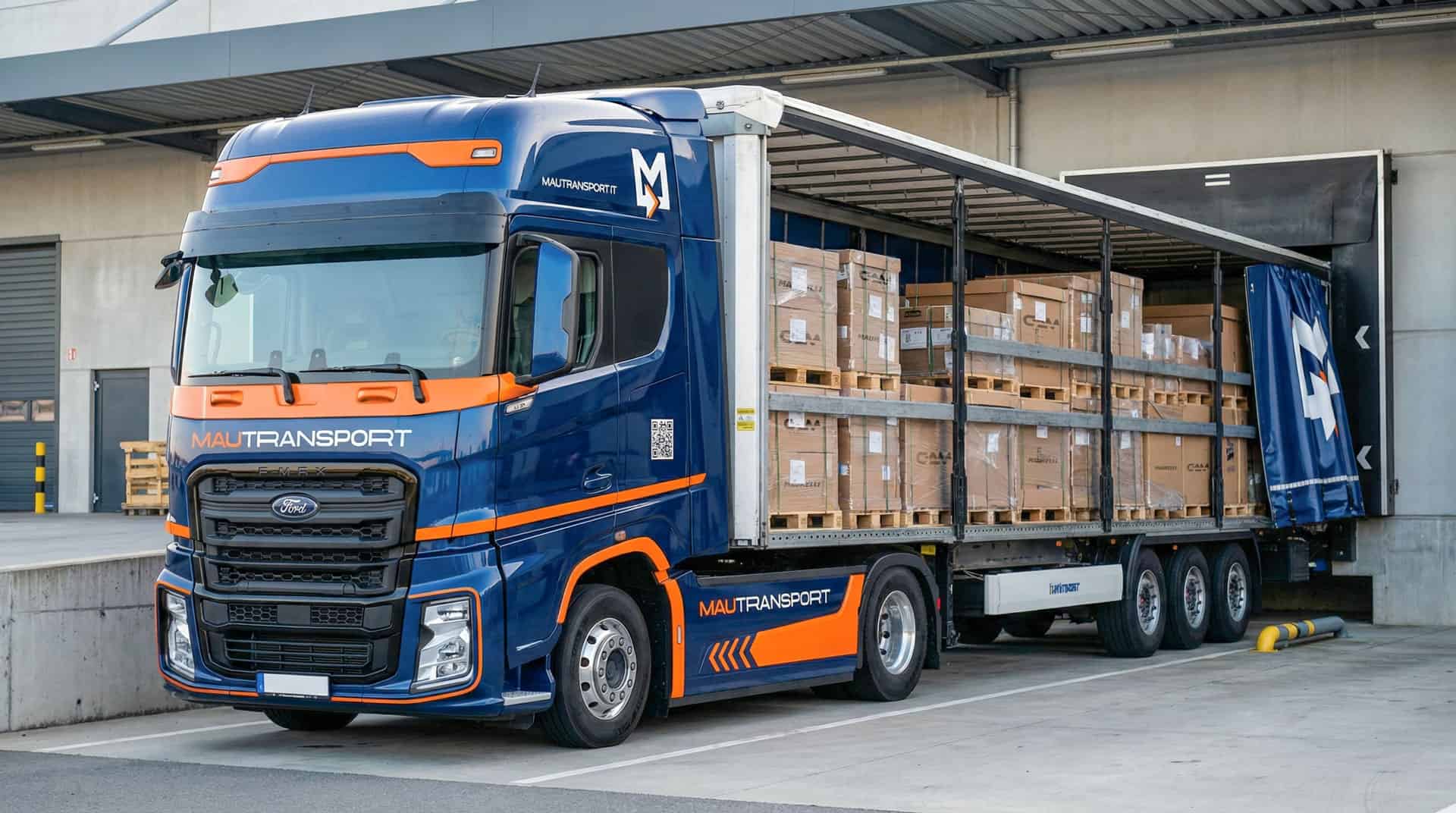 Veicolo industriale Ford Trucks Mautransport in baia di carico, con telone laterale aperto che mostra bancali di ricambi GAM pronti per la distribuzione.