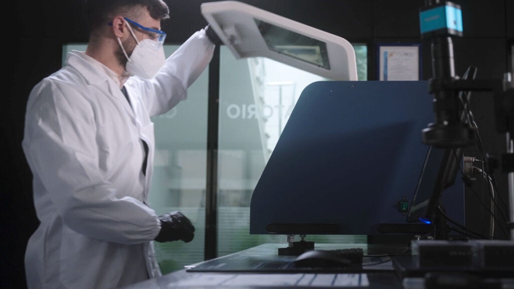 Tecnico specializzato Formau in camice e mascherina utilizza un'apparecchiatura diagnostica di precisione all'interno di un laboratorio.