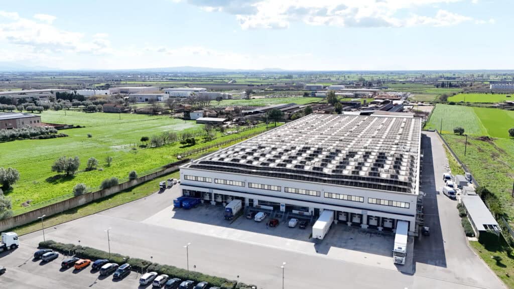 Veduta aerea del grande polo logistico e sede centrale del Maurelli Group, circondato dal verde con veicoli industriali nei piazzali di carico.